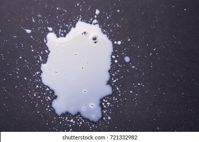 White Milk Spilled And Splash On The Dark Floor Surface. Top View