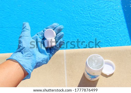 White mini chlorine tablet in the hand of a service worker for disinfection of swimming pools. The beginning of the swimming season is hot summer.