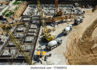white mixers and yellow crane at the construction site of a building in summer days