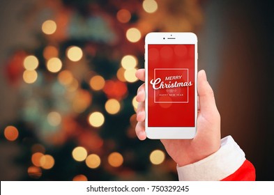 White mobile phone in Santa Claus hand close up. Merry Christmas greeting on phone display. Christmas bokeh lights in background. - Powered by Shutterstock