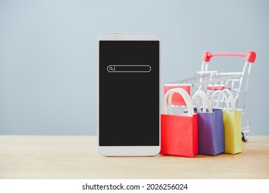 White Mobile Phone With Search Bar And Clipping Path On Touchscreen ,shopping Cart , Shopping Bag On Wood , Business, Online Marketing, E-commerce Concept