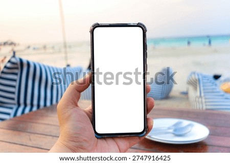 A white mobile screen with a background of a beach in the evening, filled with many people relaxing by the sea.