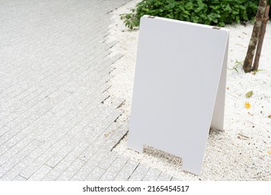 White Mock Up Wooden Sign Board On Concrete Floor. Blank White Sign Outside In Daytime.