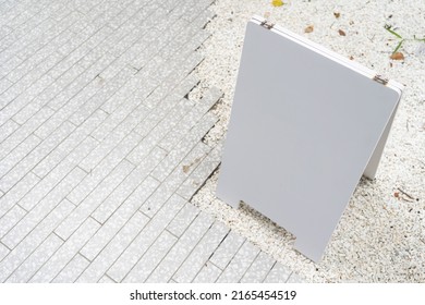 White Mock Up Wooden Sign Board On Concrete Floor. Blank White Sign Outside In Daytime.