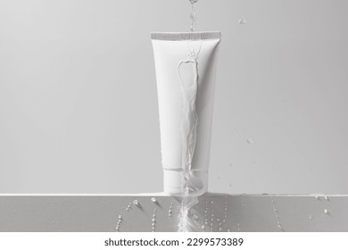 White mockup of a tube of cream with a stream of water and drops on an isolated background. Daily skincare and body care routine. Template for beauty products - Shutterstock ID 2299573389