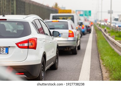 White modern car stuck in traffic jam on a highway. Concept of rush hour during commuting in a vehicle. Queue of automobiles waiting in line on asphalt covered road.