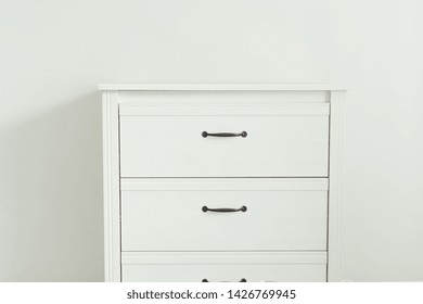 White Modern Chest Of Drawers Near White Wall.  Furniture With Drawers In A Frame.