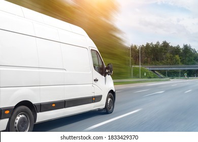 Белый современный грузовой микроавтобус для доставки небольших грузов, быстро движущийся по автомагистрали в городской пригород. Экспресс-сервис по распределению бизнеса и логистике. Микроавтобус едет по шоссе в солнечный день