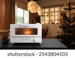 white modern design toaster oven , countertop or convection oven is on black wooden table in nice Christmas decorate modern design kitchen room is used to bake a cookies for the party during Christmas