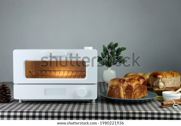 white modern design toaster oven , countertop\
or convection oven is on the table with homemade sweet potato\
butter toast breads on grey cement wall background in the kitchen\
room for breakfast
