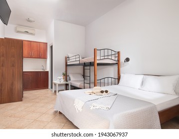 White Modern Interior Of Family Suit Bedroom With Classic Double Bed, Bunk Bed With Metal Stairs, Wooden Kitchen Cabinets In Single Space Of Small Room Hotel Studio Apartment