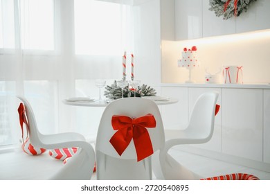 White modern kitchen table setting with festive Christmas decor and red bows on chairs