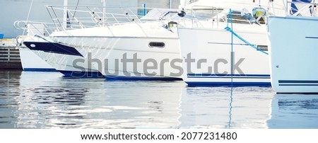 White modern sailing boats (for rent) moored to a pier in a yacht marina on a clear summer day. Sport and recreation theme. Sweden