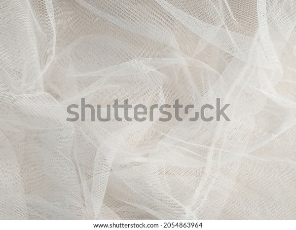 White\
mosquito net fabric texture with folds. Wavy chiffon background.\
Full frame of crumpled white cloth material texture. Abstract white\
net fabric pattern for patterns and\
designs.