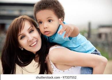 A white mother with a son of an african descend relaxing together outdoor.