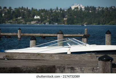 White motorboat at Kirkland marina with Lake City neighborhood and Olympic mountains in the background