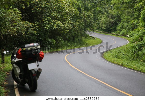White motorcycle\
is traveling in the\
forest.\
