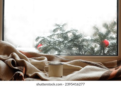 white mug of hot drink on a windowsill with warm blanket, when behind is window Christmas - Powered by Shutterstock