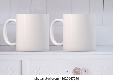 White Mug Mockup with 2 mugs, on a white dresser. Perfect for businesses selling mugs, just overlay your quote or design on to the image.