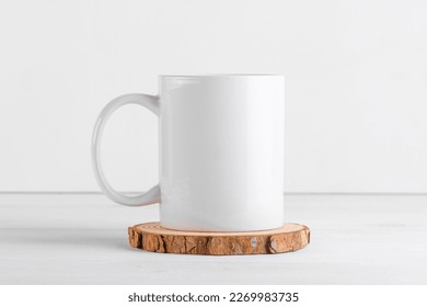 White mug mockup with blank copy space for your advertising text message or promotional content on a wooden podium on white background. Coffee mug mock up, close up