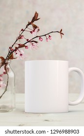 White Mug Mockup - Easter Or Spring Theme. Blank White Mug Next To Blossom  In A Glass Vase. Perfect For Businesses Selling Mugs, Just Overlay Your Quote Or Design On To The Image.