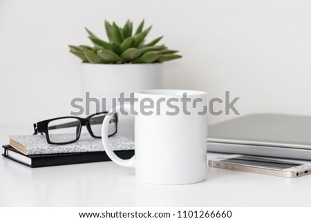 White mug mockup, modern workspace with laptop, notebooks, eyeglasses and succulent plant