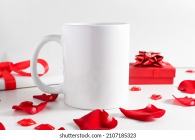 White Mug Mockup On Wooden Table With Gifts And Red Rose Petals Front View. Empty Template With Copy Space For Design And Logo.