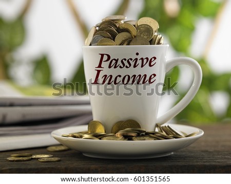 white mug written passive income with coins inside, finance conceptual.