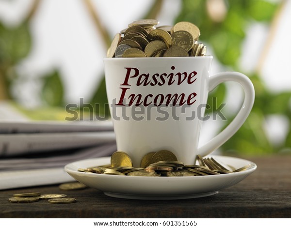 white mug written passive income with coins inside, finance conceptual.