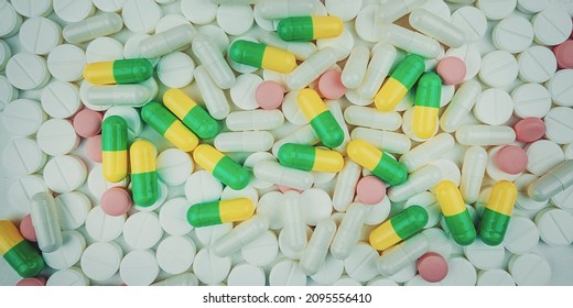 White And Multi Colored Pills On White Background Top View. Big Pharma Business And Industry.