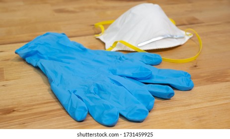 White N95 Face Mask And Blue Nitrile Gloves On Wooden Table For Virus Prevention.