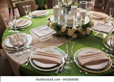 White napkins lie on plates on round green table