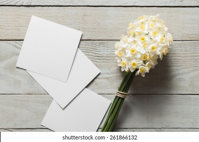 White Narcissus Flowers And Blank Paper Pieces On Wooden Background