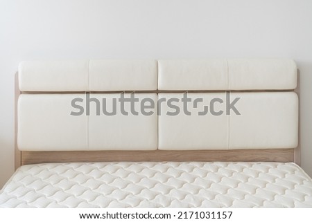 White natural leather bed headboard. Oak wood bed with mattress.