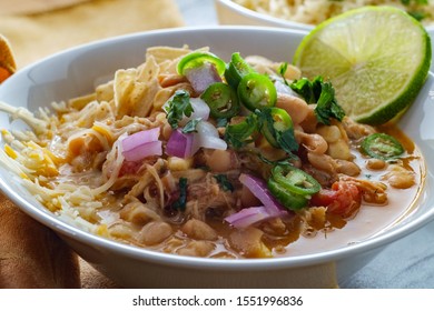 White Navy Bean Chicken Chili With Tortilla Strips Lime Cilantro And Shredded Cheese Garnish