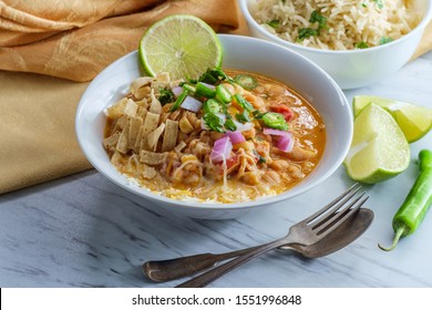 White Navy Bean Chicken Chili With Tortilla Strips Lime Cilantro And Shredded Cheese Garnish