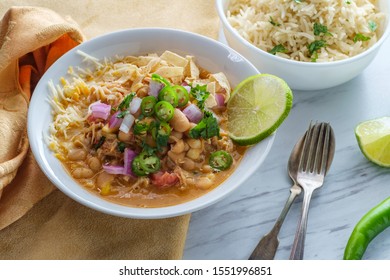 White Navy Bean Chicken Chili With Tortilla Strips Lime Cilantro And Shredded Cheese Garnish