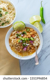 White Navy Bean Chicken Chili With Tortilla Strips Lime Cilantro And Shredded Cheese Garnish