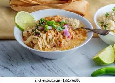 White Navy Bean Chicken Chili With Tortilla Strips Lime Cilantro And Shredded Cheese Garnish