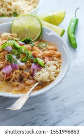 White Navy Bean Chicken Chili With Tortilla Strips Lime Cilantro And Shredded Cheese Garnish