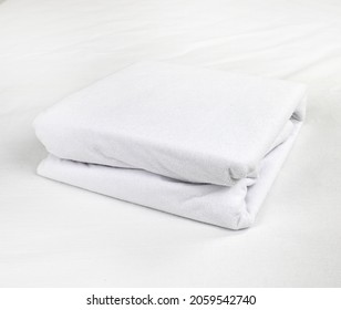 White, Neatly Folded Terry Waterproof Mattress Topper. Mattress Covers. Protection Of The Bed From Water And Baby Secretions. Production Of Mattress Covers From Cotton Materials