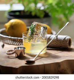 White Negroni Cocktail With Clear Ice And Silver Barware On A Wooden Board