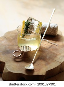 White Negroni Cocktail With Clear Ice And Silver Barware On A Wooden Board