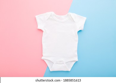 White new baby bodysuit on light pink blue table background. Pastel color. Closeup. Empty place for text or logo on apparel.