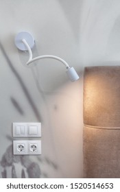 White Night Light Lamp On Wall Over Socket And Switch, Near Bed In Bedroom. Vertical Photo Of Modern Apartment With Contemporary Interior