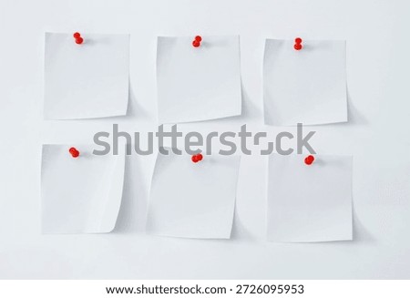 White note papers with red thumbtacks on the board. 