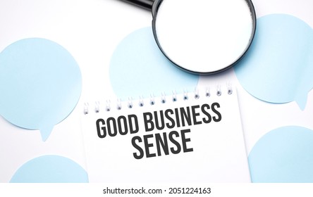 White Noteapad And Magnifier On Blue Speech Bubles. Text GOOD BUSINESS SENSE. Business Concept