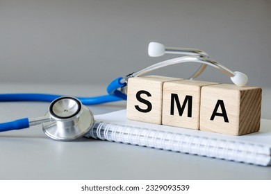 white notebook, Medical stethoscope and wooden blocks with the medical abbreviation SMA for spinal muscular atrophy, severe genetic disease, Beautiful gray background, Medical concept - Shutterstock ID 2329093539