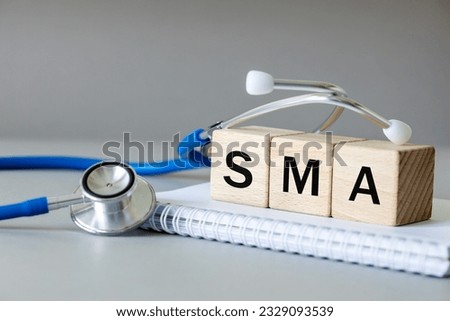 white notebook, Medical stethoscope and wooden blocks with the medical abbreviation SMA for spinal muscular atrophy, severe genetic disease, Beautiful gray background, Medical concept