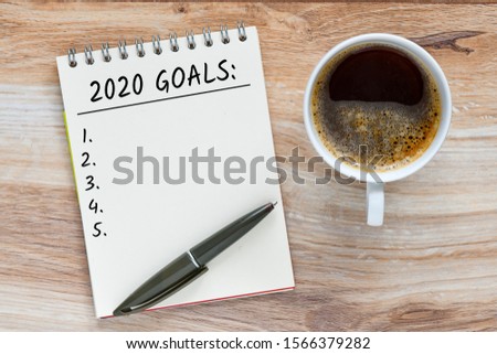 White notebook for notes, pen, wooden background. Top view Copy space, 2020 Goals text concept.